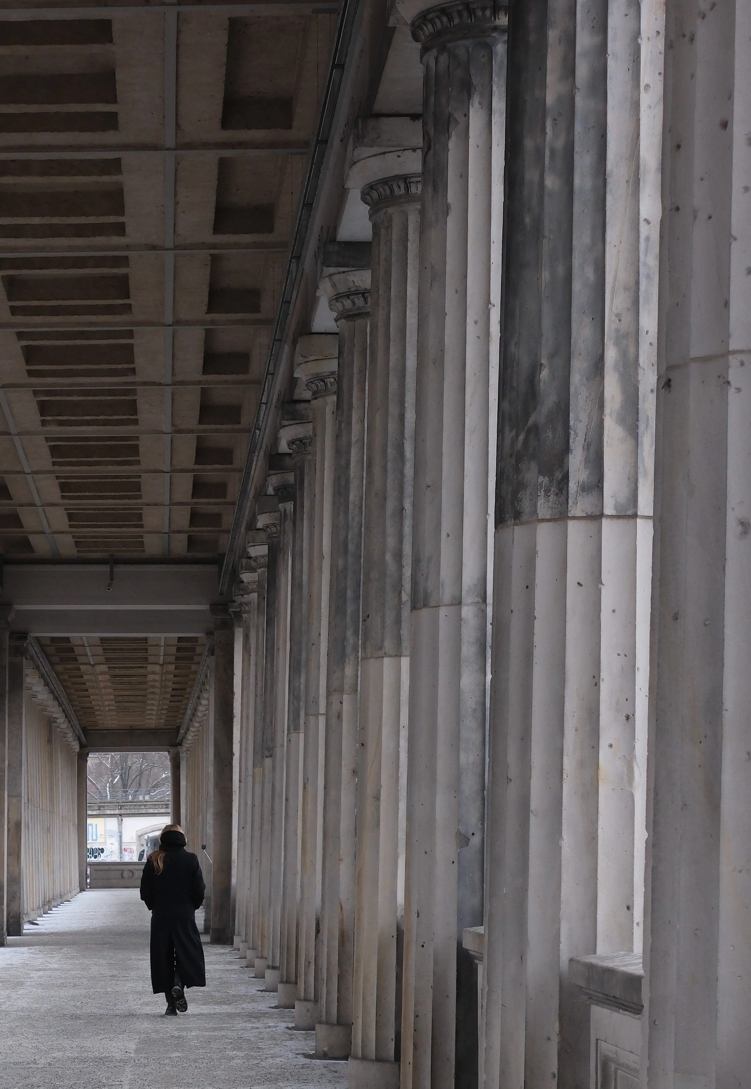 Frau läuft zwischen Säulen von Kamera weg